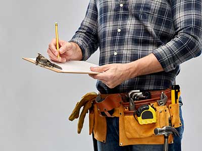 Contracting with a tool belt writing something down on their clipboard